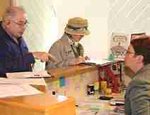 Two People Standing Behind a Counter and Talking to a Woman